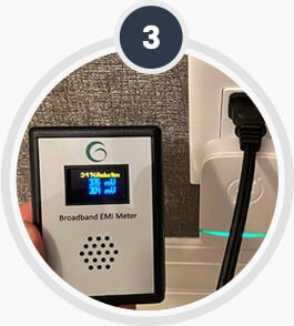 A small meter held near the unit to confirm operation